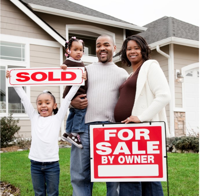 A happy family standing outside a home with a sign written, 'for Sale by Owner'. Their young child is holding up a sign written, 'SOLD'.