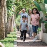 a family of 4- 2 young children and parents walking on a path. The children happily run ahead of the parents.