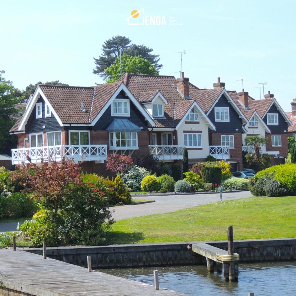 multi unit homes sitting in a well manicured garden with a lake at the front.
