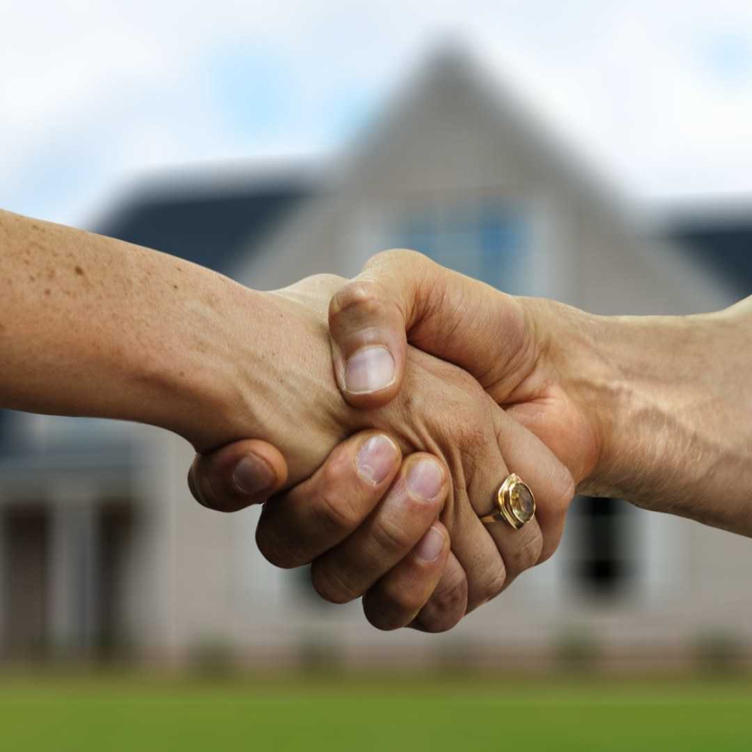 2 hands shaking in a firm way. behind the hands is a single unit property.