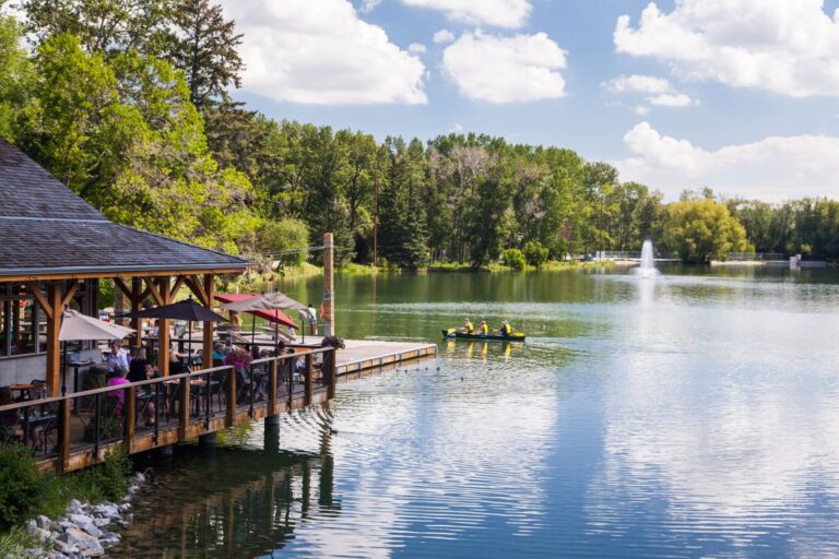 a beautiful park of a lake with small boat and restaurant on the left.