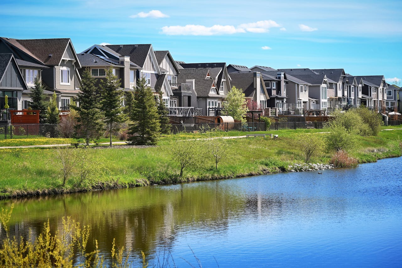 A row of houses with trees by a lake.