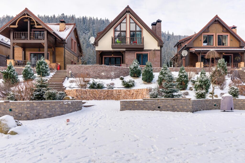 3 cottages lined up. snow and bushes are infront of them.