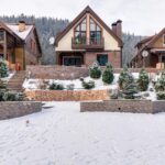 3 cottages lined up. snow and bushes are infront of them.