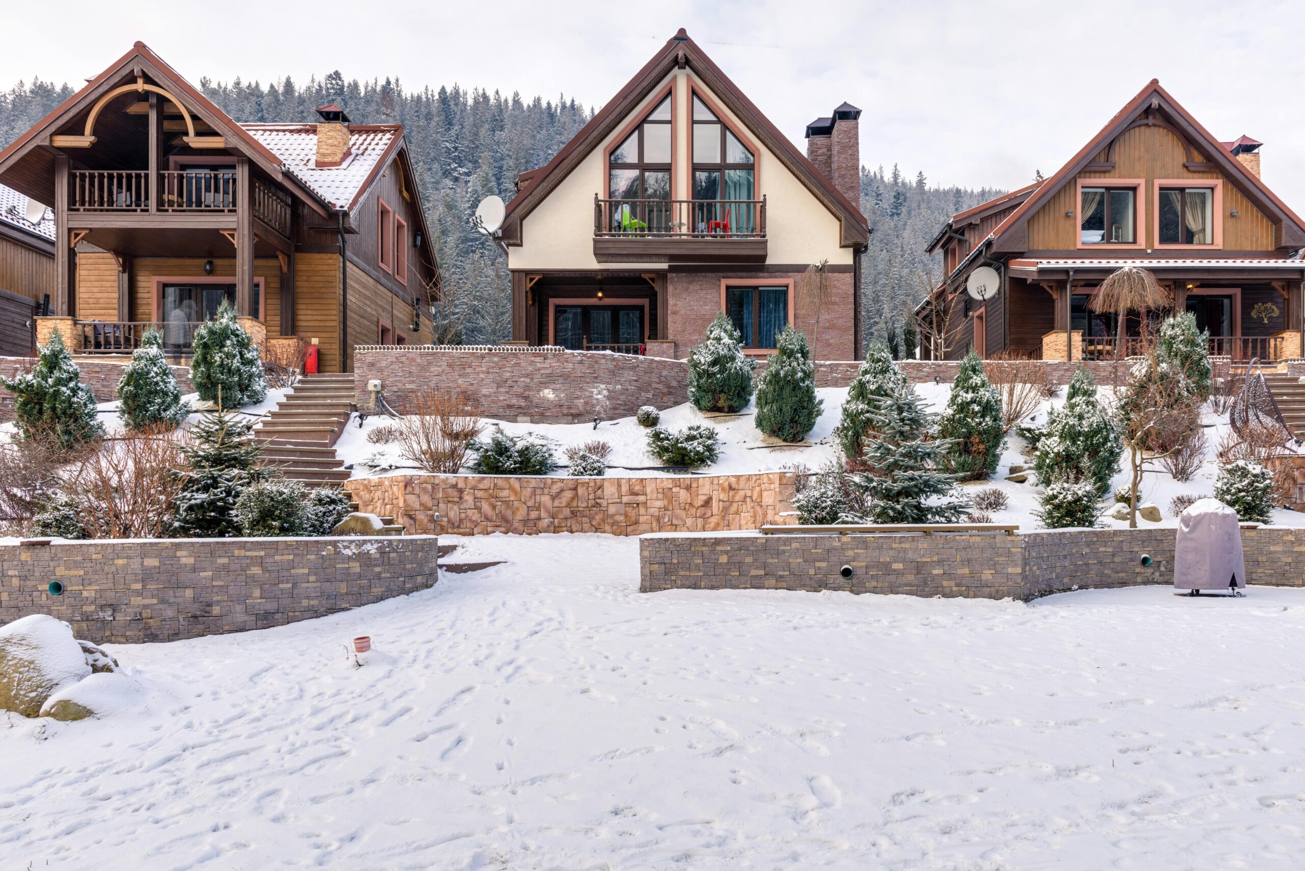 3 cottages lined up. snow and bushes are infront of them.