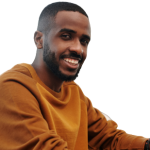 A smiling gentleman sitting at a table wearing a brown sweater, looking at the camera.